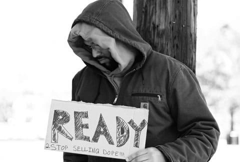 A man holding up a sign that says " ready for selling drugs ".
