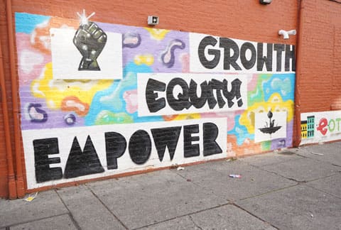 A wall with graffiti on it that says " growth equity empower ".